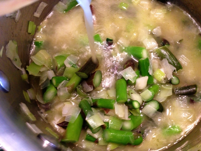Slowly add chicken broth to the vegetables and cover the pot, simmering for ten minutes.