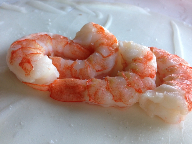 Remove tails from cooked shrimp and lay four on top of the spring roll skin.